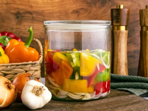 Buntes eingelegtes Gemüse im Glas: Paprika zum Abnehmen, Zwiebeln und Knoblauch.