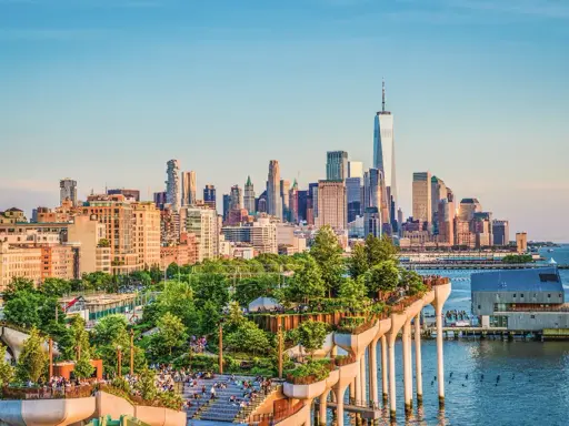 En grönskande park på pelare med New Yorks skyline i bakgrunden. Perfekt för tips på nya upplevelser i New York.
