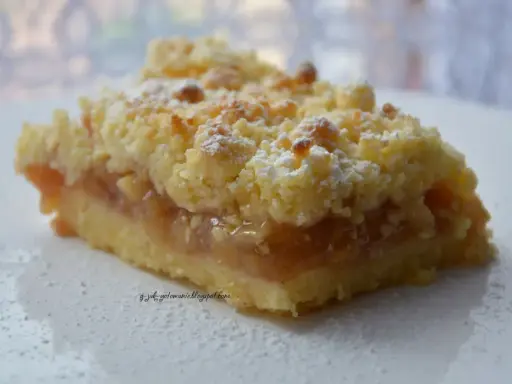 Pyszna tarta z jabłkami, posypana cukrem pudrem, kusi chrupiącą kruszonką i aromatycznym nadzieniem.
