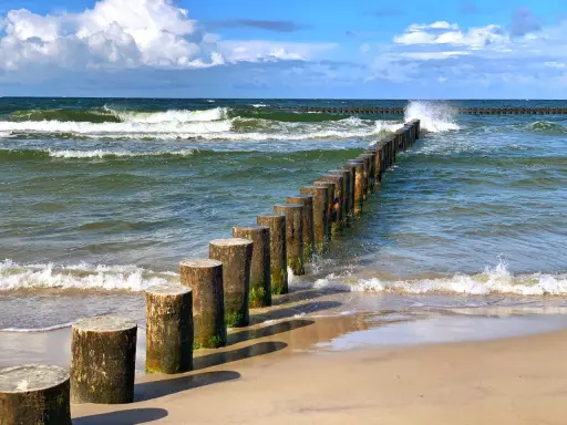 Jastrzębia Góra co zobaczyć: falochrony na plaży i wzburzone morze. Idealne miejsce na spacer i podziwianie Bałtyku.