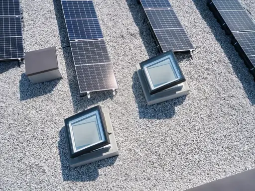 Vue aérienne d'une maison toit plat avec panneaux solaires et deux fenêtres de toit.