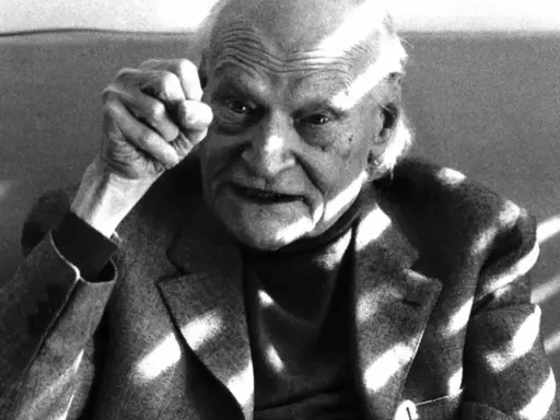 Ritratto di un anziano con pugno alzato, in memoria di Ungaretti. Le rughe sul volto e la luce che lo illumina creano un'atmosfera intensa.