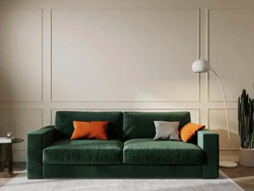 Elegancki salon w odcieniach butelkowej zieleni i beżu. Miękka sofa, nowoczesna lampa i kaktus tworzą przytulną atmosferę.
