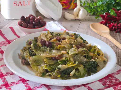 Scarola in padella con olive, pinoli e uvetta, un contorno saporito e colorato.