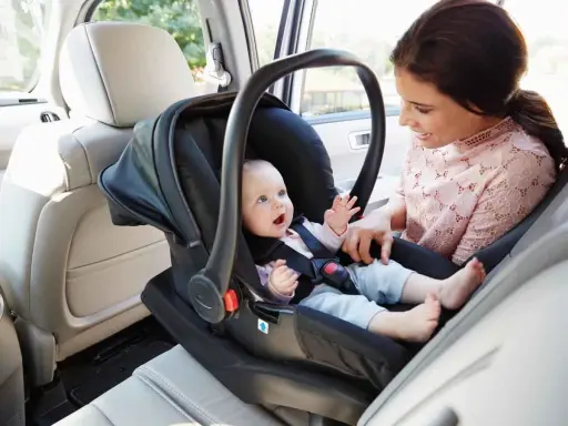 Uśmiechnięta mama patrzy na swoje dziecko w foteliku samochodowym. Ten fotelik dla dziecka do 20 kg zapewnia bezpieczeństwo maluchowi podczas podróży.
