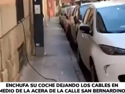 Un coche eléctrico se carga en la calle, con cables cruzando la acera. Una forma poco convencional de como cargar coche electrico en la calle.