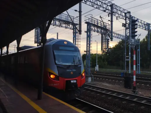 Pociąg na peronie w Skierniewicach o zachodzie słońca.