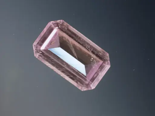 Un cristallo rosa sfaccettato, simile a uno smeraldo, fluttua su uno sfondo scuro. Un esempio di pietre più costose.