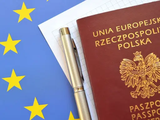 Polski paszport, długopis i flaga Unii Europejskiej.