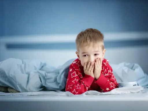 Zmartwiony chłopiec w piżamie z gwiazdkami leży w łóżku. Martwi się, że dziecko nie sika od 24 godzin.