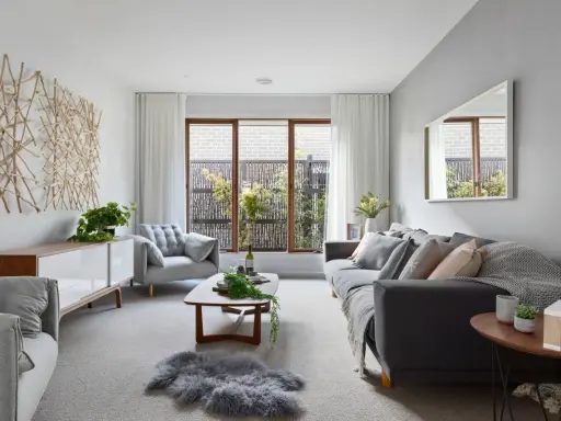 Elegante salón donde el gris y beige combinan a la perfección, con sofás cómodos, mesa de centro de madera y una original decoración de ramas en la pared.