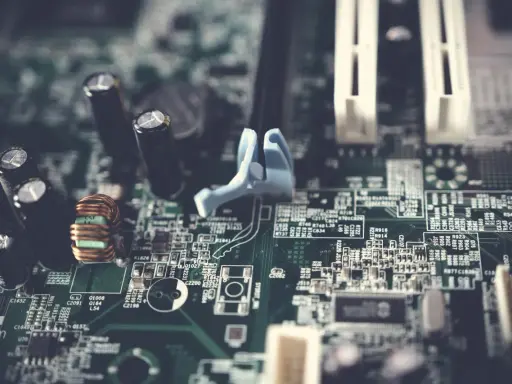 Fragment płyty głównej w formacie extended ATX z widocznymi kondensatorami, cewką i złączami.