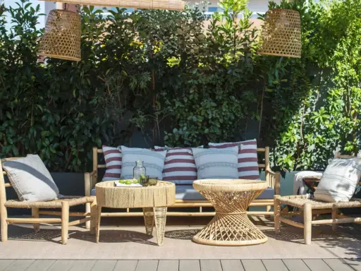 Un rincón acogedor para decorar terraza ático. Muebles de ratán, cojines y lámparas de mimbre crean un oasis natural.