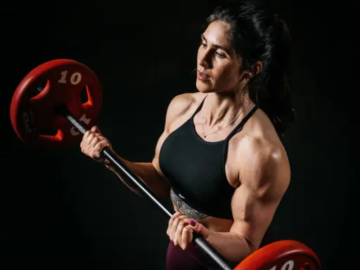 Eine starke Bodybuilderin Frau hebt eine Hantel. Ihre Muskeln sind deutlich sichtbar.