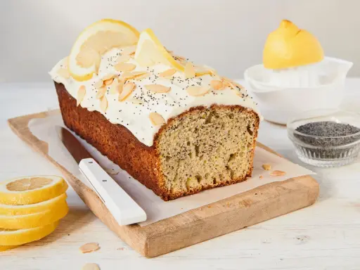 Saftiger zitronenkuchen mit mohn, garniert mit Mandelsplittern und Zitronenscheiben.
