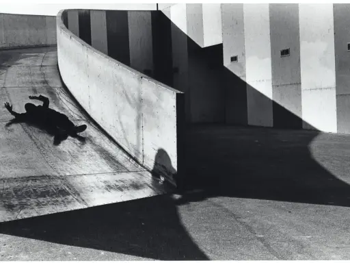 A silhouetted figure lies on a curved concrete ramp, arms outstretched, at the Janet Borden Gallery.