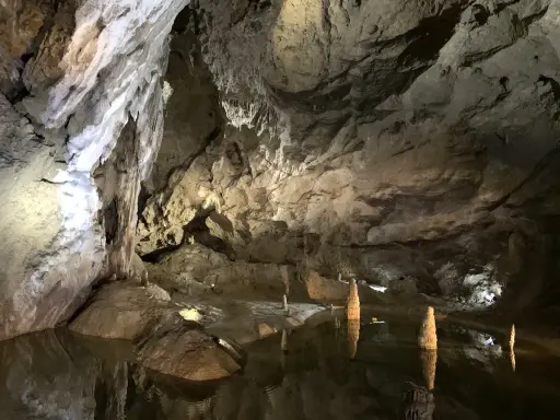 Wnętrze jaskini Bielskiej z wodą i stalagmitami.