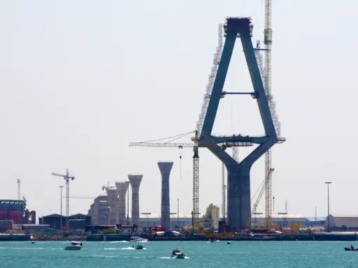 Construcción de un puente con pilares de hormigón y grúas, sobre el mar.