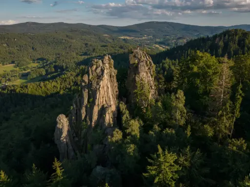 Skaliste szczyty, jak sokolik duży, górują nad lasem. Na jednym z nich platforma widokowa z turystą.