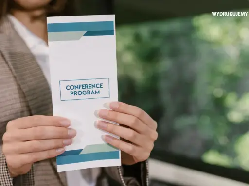 Oto jak wygląda ulotka z programem konferencji, trzymana w dłoniach.