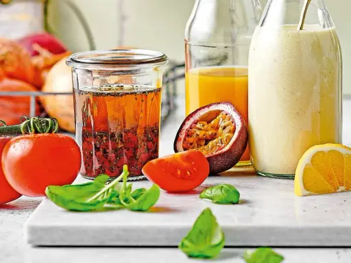 Ein Glas mit asiatischem Salatdressing, Tomaten, Passionsfrucht, Orange und Kräutern.