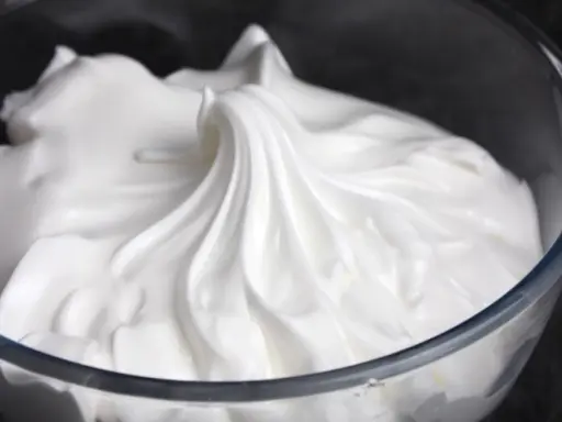 Merengue italiano esponjoso y brillante en un bol de cristal, listo para decorar postres.