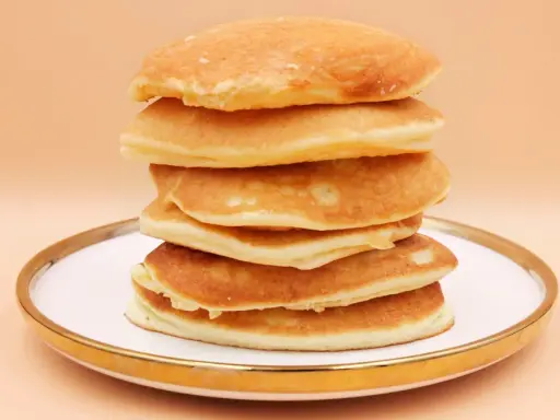 Stos puszystych, złotych pancake'ów na talerzu. Idealny przepis na śniadanie.