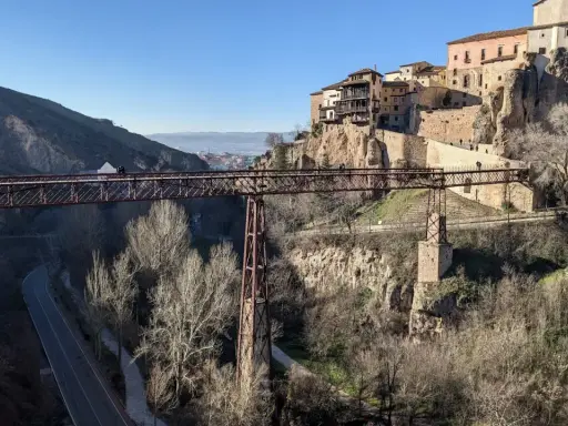 Puentes de Cuenca: una estructura de hierro cruza un barranco, con casas colgando de acantilados rocosos al fondo.