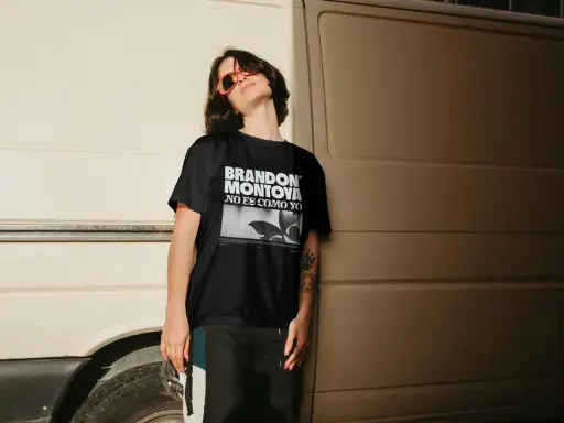 Joven con gafas de sol naranjas y camiseta negra con el diseño "BRANDON MONTOYA NO ES COMO YO".