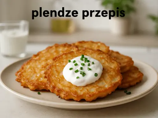 Plendze (placki ziemniaczane) z kwaśną śmietaną i szczypiorkiem na talerzu.