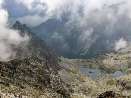 Widok na skaliste zbocza i dwa jeziora w Tatrach, rysy od strony polskiej. Mgła otula szczyty.