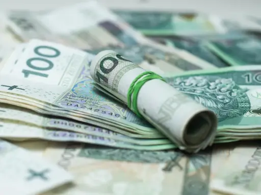Zrolowane banknoty 100 zł, gotowe do spłaty zadłużenia u komornika przez osobę trzecią.