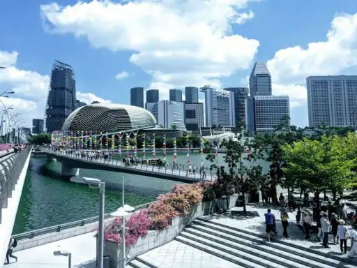 Fakta om Singapore: En bro med flaggor leder mot en futuristisk skyline med Esplanade-teatern.