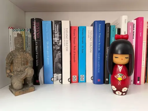 Statua guerriero terracotta e una collezione di libri di Tiziano Terzani, tra cui "La fine è il mio inizio" e "Un altro giro di giostra".