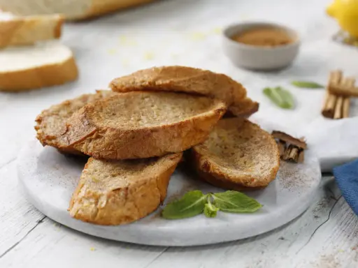 Torrijas al horno doradas y crujientes, espolvoreadas con canela, listas para disfrutar.