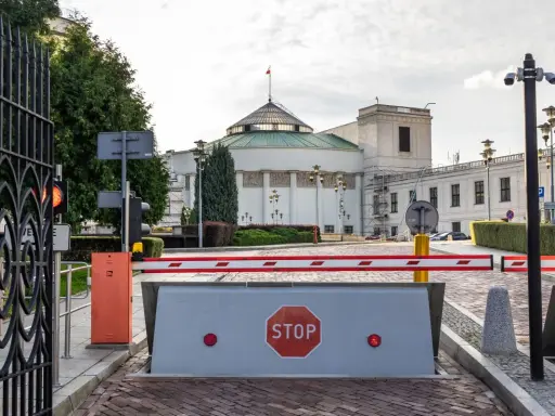 Brama wjazdowa do Sejmu, symbolizująca immunitet poselski, z barierą i znakiem STOP.