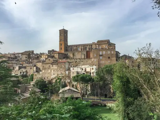 Panoramica dell'antico borgo di Sutri, con le sue case in pietra arroccate su una collina e una maestosa cattedrale con campanile.
