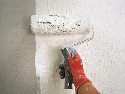 Mit einem speziellen Roller wird eine Strukturpaste aufgetragen, um eine interessante Wandgestaltung zu erzielen. Das Ergebnis erinnert an **Styropor spachteln** für eine einzigartige Textur.