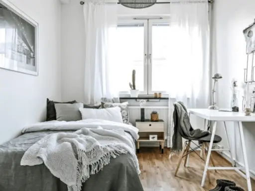 Chambre 10m2 lumineuse avec lit confortable, bureau et fenêtre. Un cactus sur le rebord de fenêtre ajoute une touche de verdure.