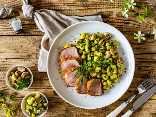 Saftige schweinelende grillen, serviert mit Kartoffeln und Pilzen, garniert mit frischer Petersilie. Ein Genuss für jeden Grillmeister!