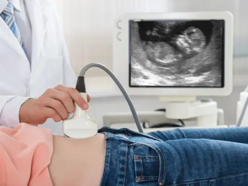 Lekarz wykonuje USG. Na ekranie widać zarodek, to 11 tydzień ciąży, który to miesiąc rozwoju dziecka.