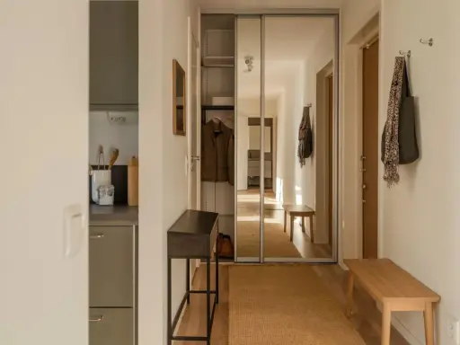 En ljus hall med spegelskjutdörrar, en smal konsol, en träbänk och en matta. Perfekt hall inspiration för en funktionell och stilren entré.