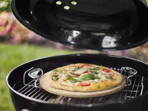 Pizza na kamieniu w grillu, gotowa do podania. Po pieczeniu czyszczenie kamienia do pizzy jest proste.