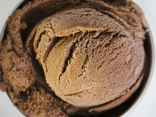 Une généreuse boule de glace au chocolat, crémeuse et givrée, dans un bol métallique.