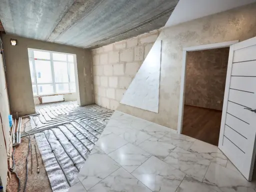 Habitación en construcción con suelo de mármol y sistema de calefacción por suelo radiante. El alicatado que es, se ve en el suelo y en la pared.