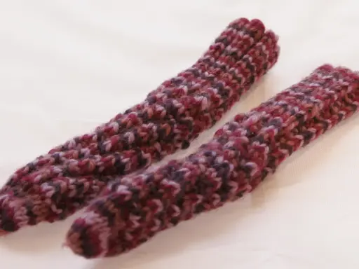 Två handstickade drops spiralsockor i ett melerat garn i vinröda och lila toner.