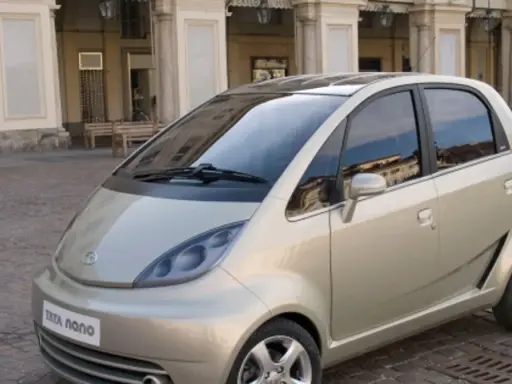 Złoty Tata Nano na brukowanym placu przed zabytkową kamienicą.