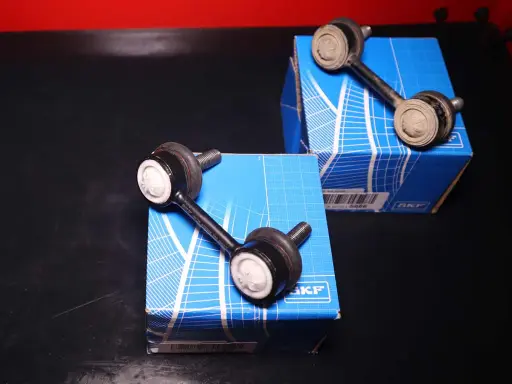 Due biellette auto SKF, componenti essenziali per la stabilità del veicolo, posizionate su scatole blu.