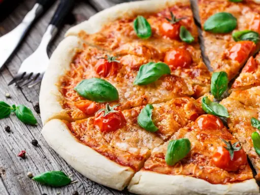 Pyszna pizza Margherita, klasyka włoskiego jedzenia, z pomidorkami koktajlowymi i bazylią na drewnianym blacie.