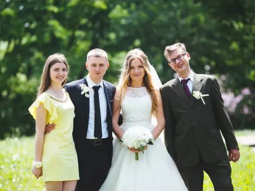 Para młoda z druhną i świadkiem. Ona w żółtej sukience, on w garniturze. Panna młoda w bieli, pan młody w granacie.